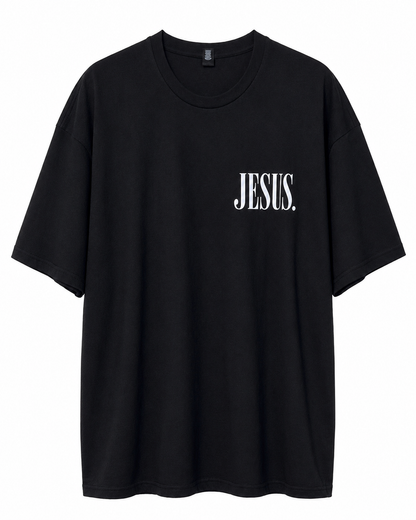Front view of black AS Colour Heavy T Shirt with bright white JESUS left chest print on white background