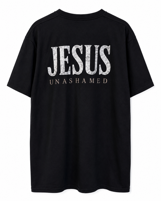 Back view of black AS Colour Heavy T Shirt with stonewashed JESUS UNASHAMED full back design on white background